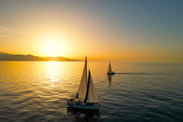Sailing Cruise vs Private Cruises in Crete: Which Is right for you? The image shows private boats sailing to sunset. 