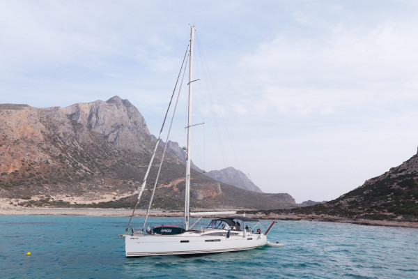 Top sailing destinations in Crete you can visit by boat. The image shows Kissamos Bay and a sailing boat.